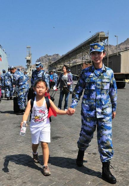 2015年3月，也门，海军女战士牵着一名小女孩的手准备登上军舰。